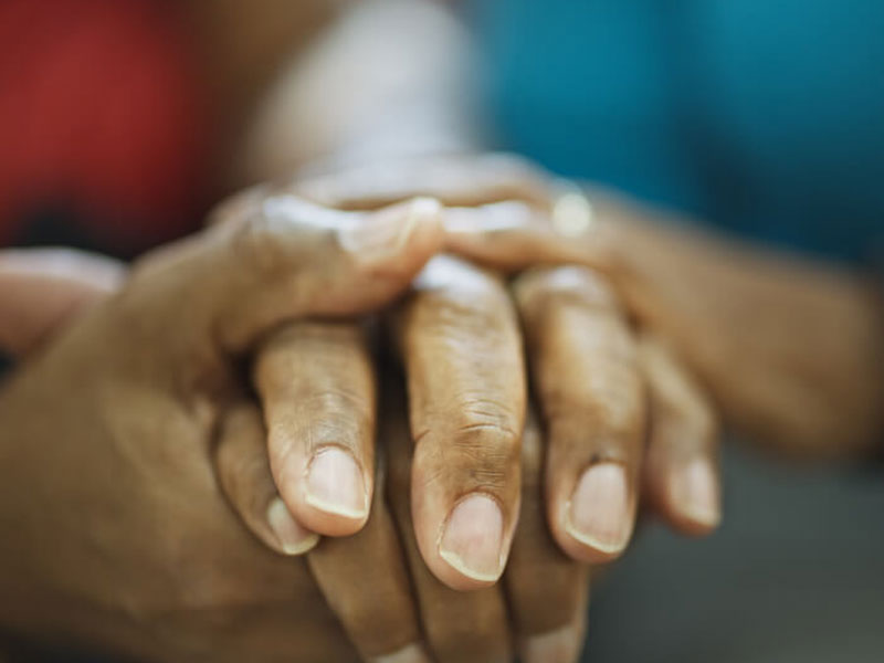 A black hospice patient, caretaker and nurse hold hands in Torrance, CA.