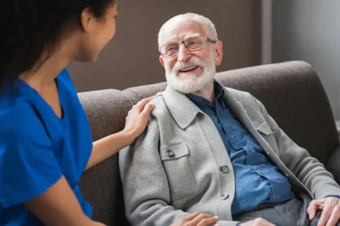 A caretaker puts her hand on the shoulder of an elderly man in hospice at home in Torrance, CA