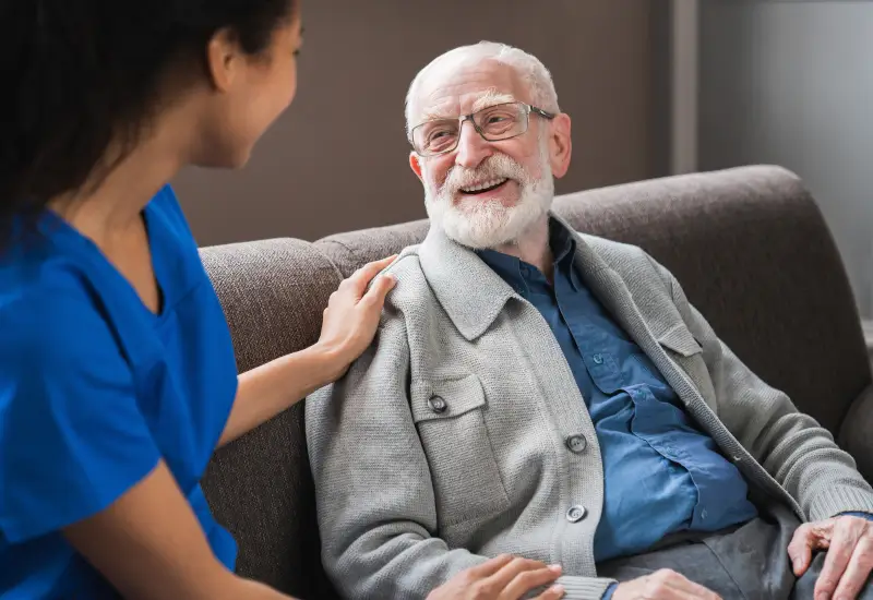 A caretaker puts her hand on the shoulder of an elderly man in hospice at home in Torrance, CA